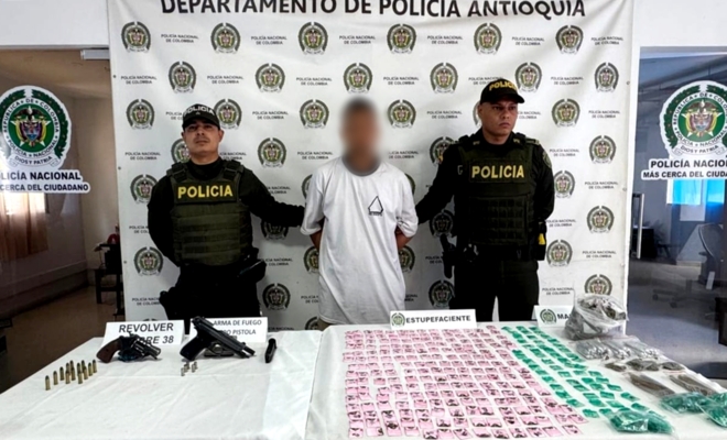 Dos polic&iacute;as custodiando a un capturado con droga y armamento