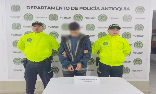 Dos polic&iacute;as con chaqueta verde de SIJIN custodian a un capturado