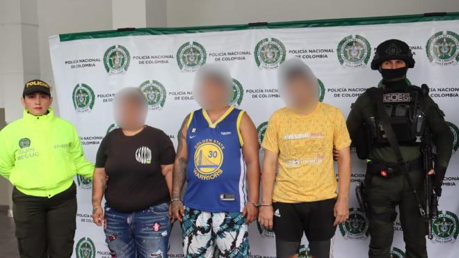 Tres personas, presuntamente capturadas, son sostenidas por dos Polic&iacute;as.