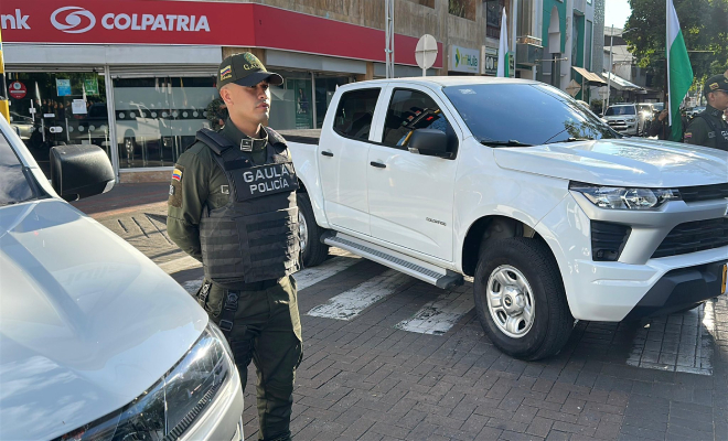 Policía de pie al lado de camionetas blancas entregadas por la Gobernación del Huila