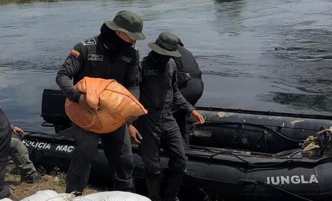 Dos funcionarios policiales cargando sacos de arena en una lancha