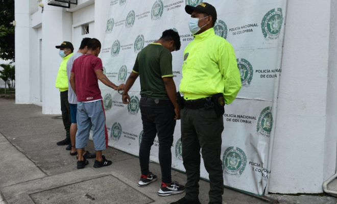 Personas capturadas-policías custodiando