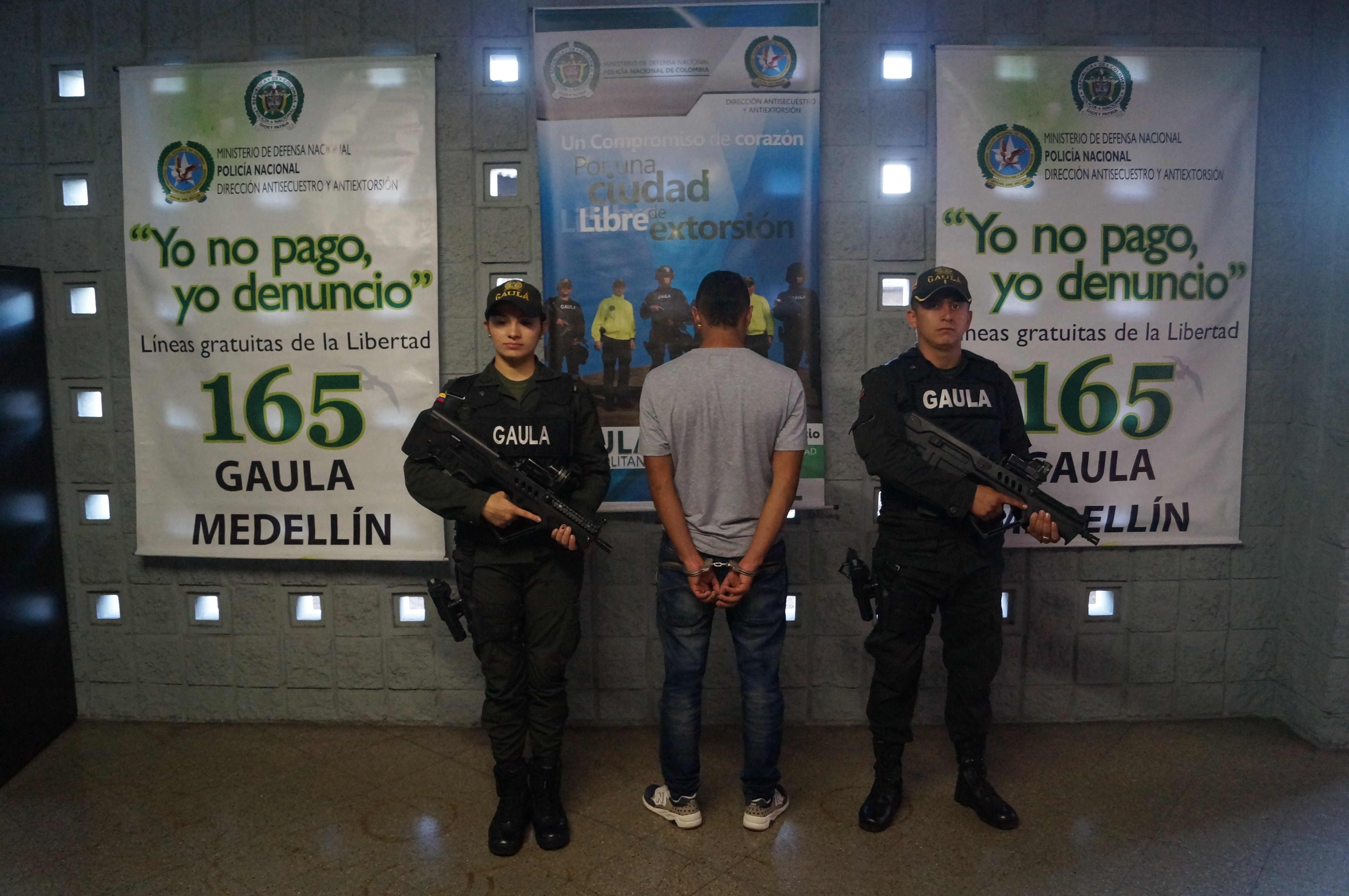 Una persona esposada de espaldas es custodiada por dos policías