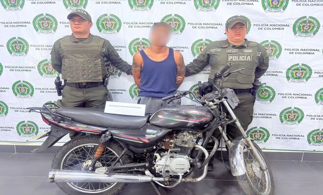 Dos uniformados con una persona capturada, junto a una motocicleta recuperada.