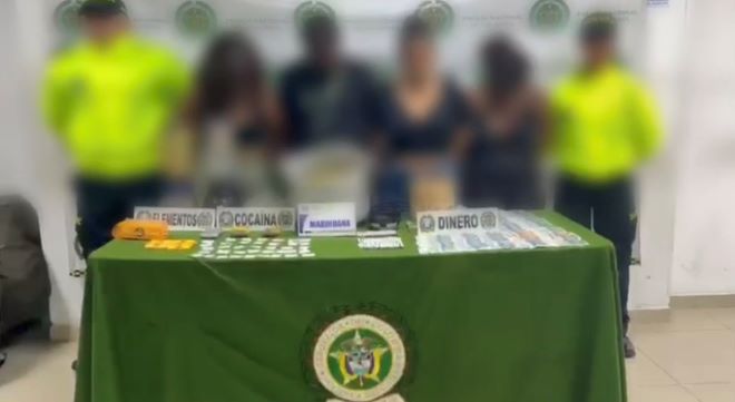 Dos polic&iacute;as al lado de cuatro personas con material incautado