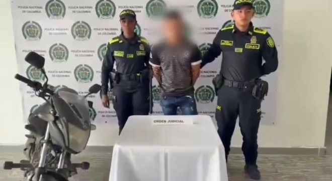 dos policías al lado de un capturado y una motocicleta