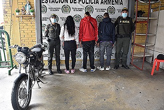 Tres personas capturadas-policías custodiando-motocicleta inmovilizada