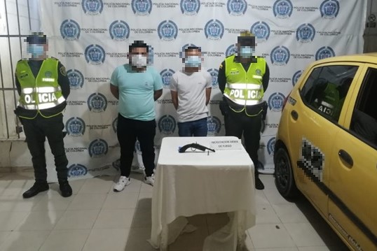 2 personas capturadas-policias custodiando-arma de fuego incautada-taxi inmovilizado