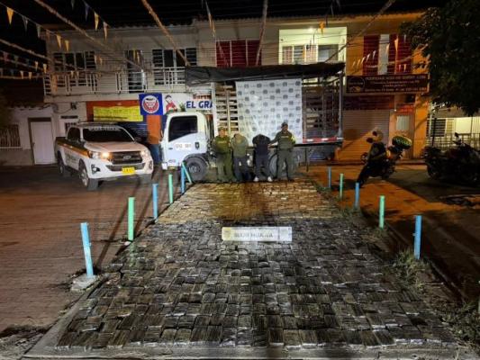 polic&iacute;as al lado de dos hombres con estupefacientes