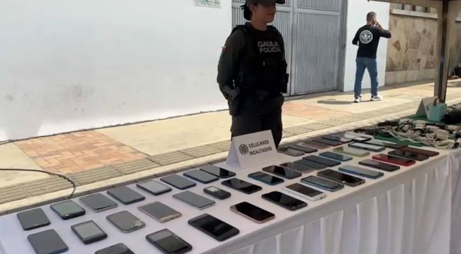 Una policía al lado de celulares incautados 